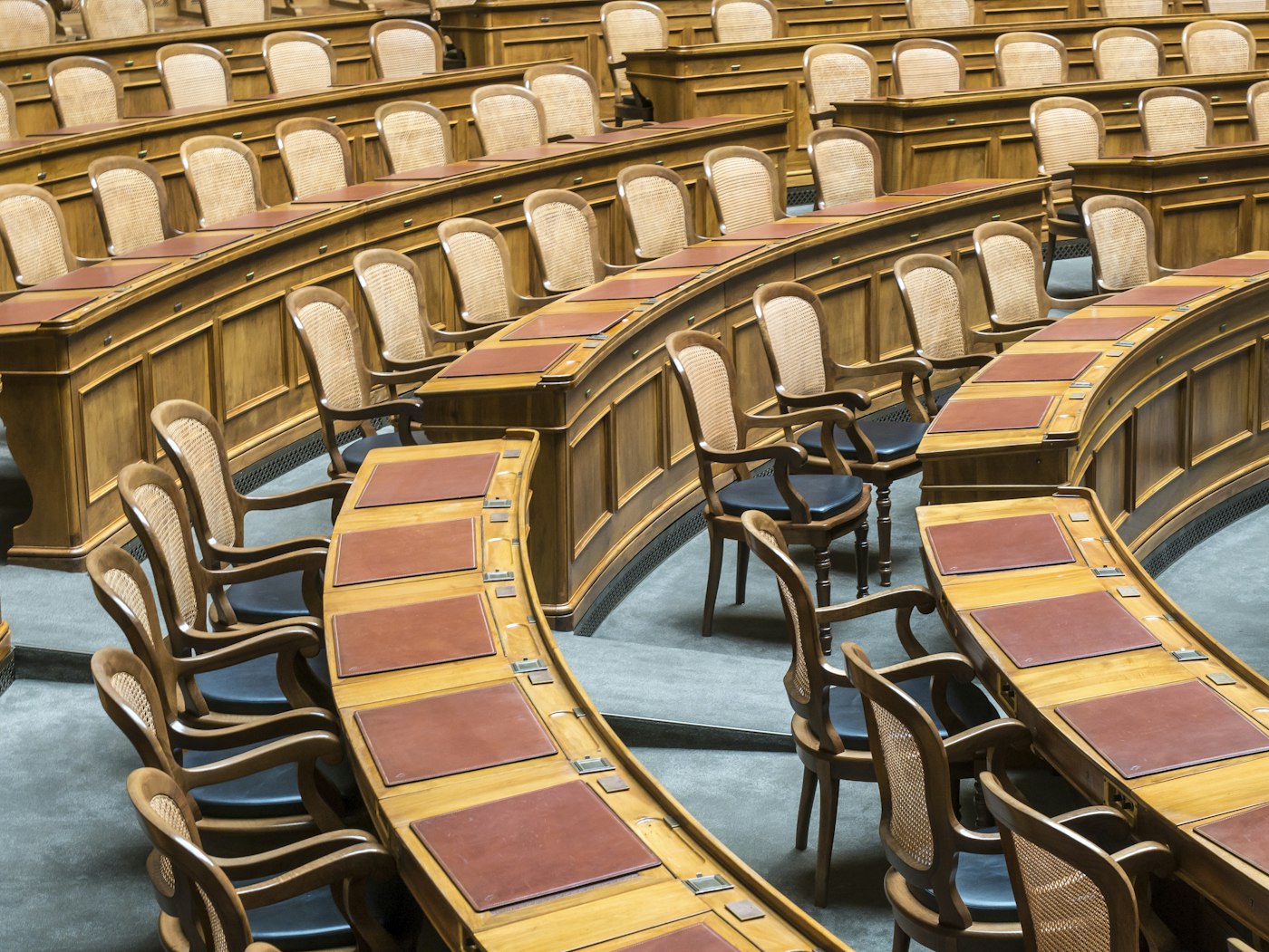 Rows of wooden desks in a legislative chamber